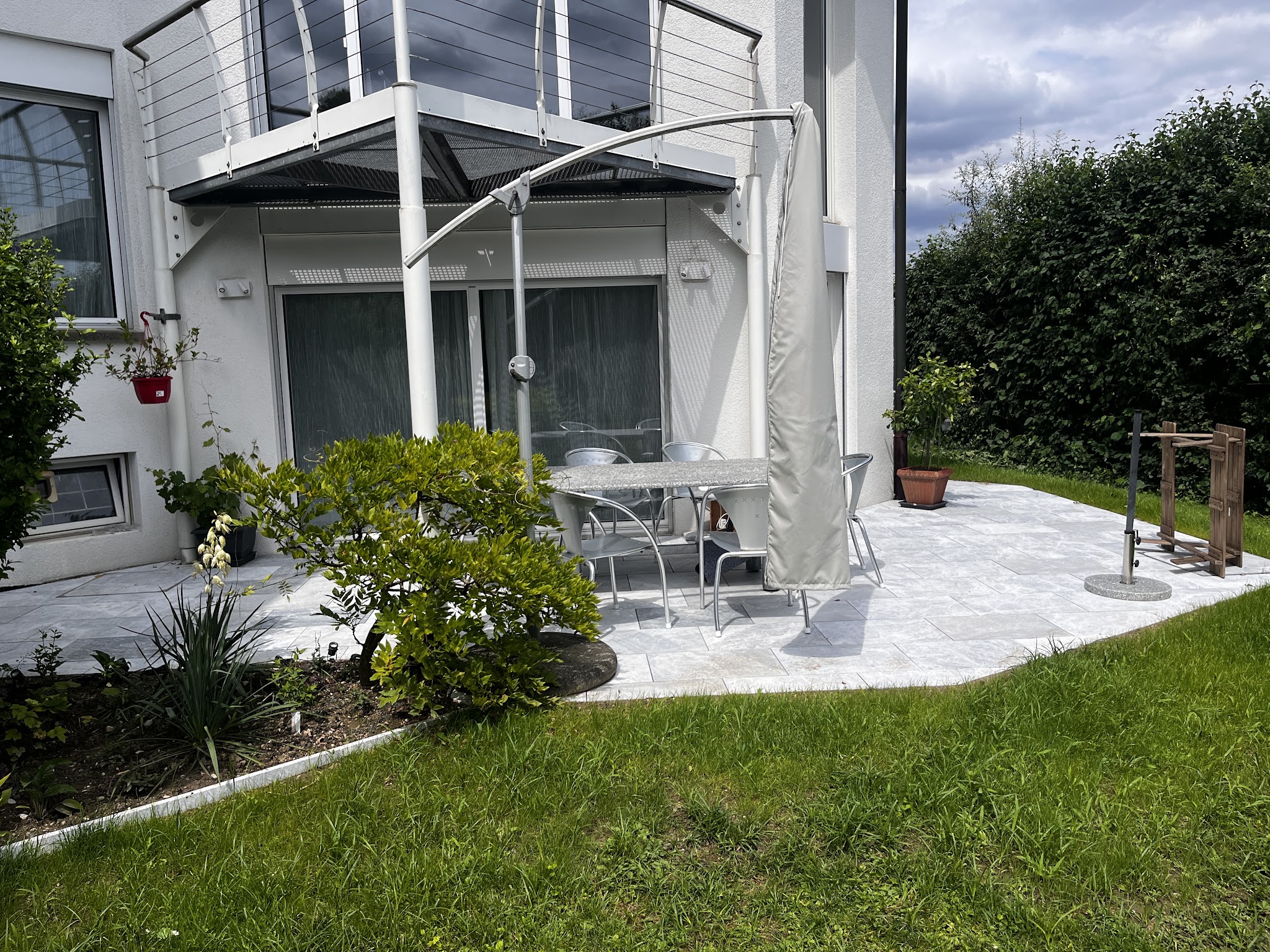 Plattensitzplatz mit Gartenmöbeln neben dem Haus