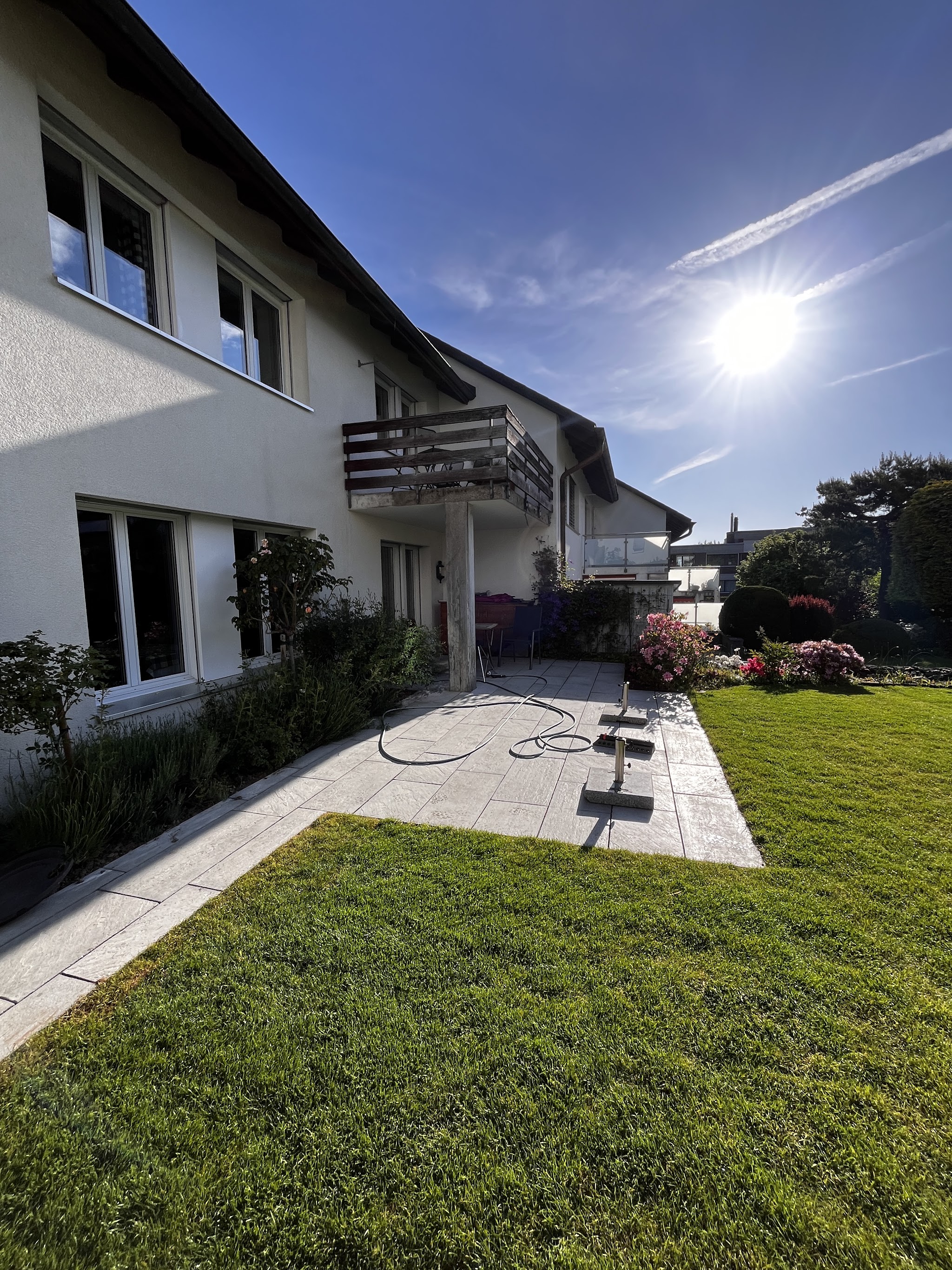 Plattenweg und Rasen an der Hausfassade