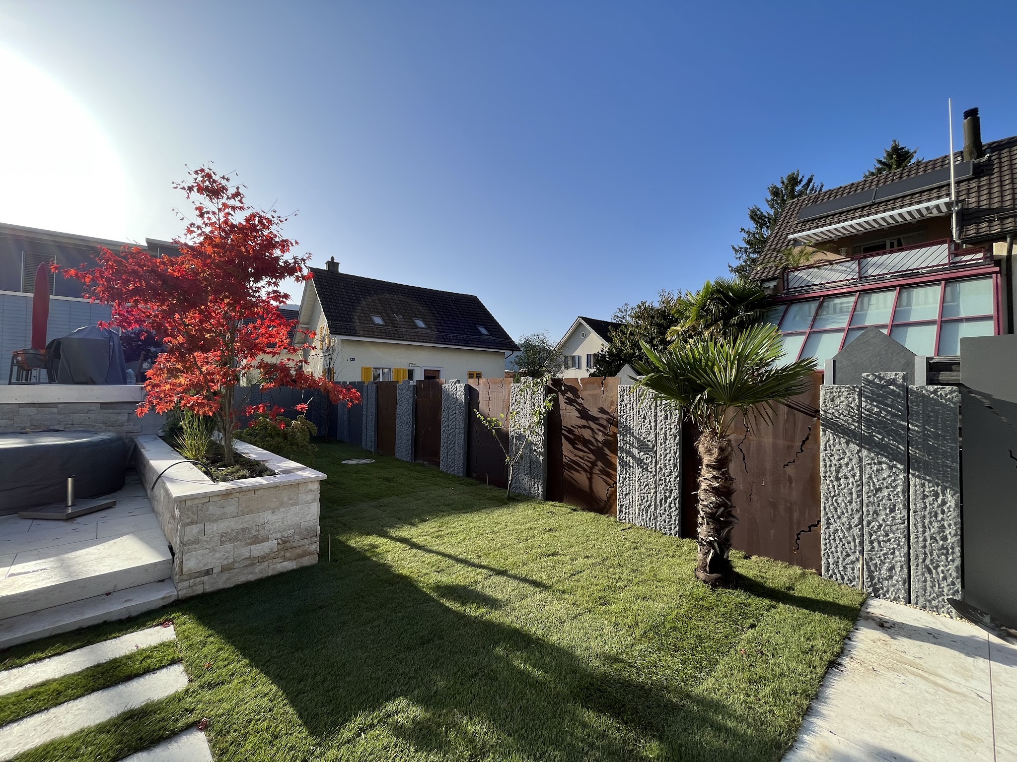 Terrasse mit rotem Ahorn, Palme und Sichtschutz